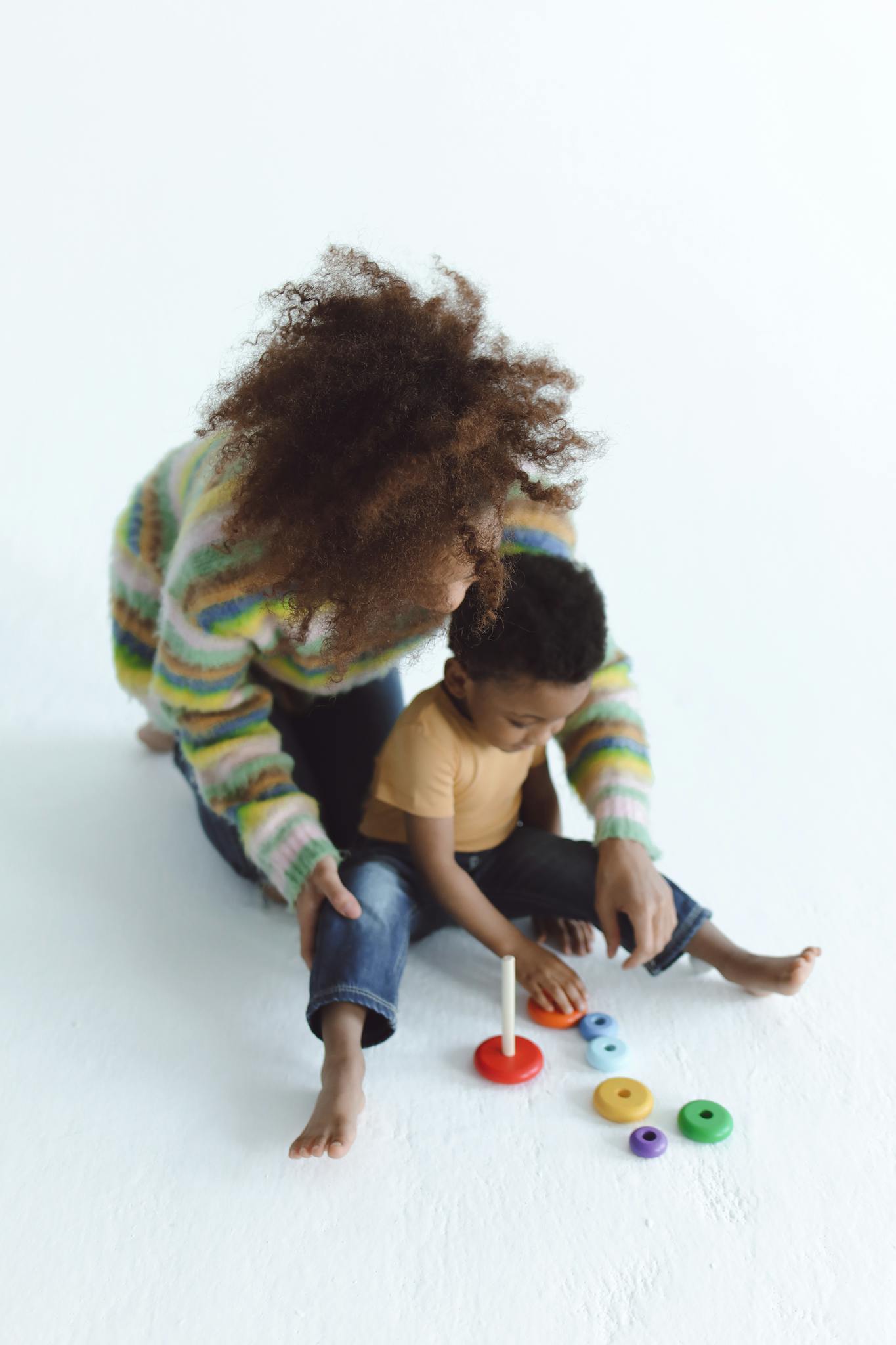 An adult and child play with colorful toys on a white background, showcasing joy and creativity.