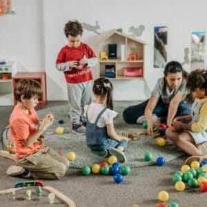 Young children and a teacher engaging in play and learning activities in a preschool setting.