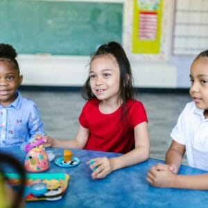 Young children enjoying a playful learning activity in a bright classroom setting.